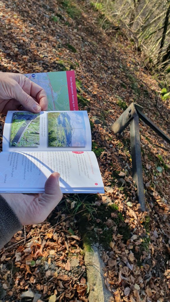 Ein Wanderer blättert die Broschüre des Klosterweges durch.
